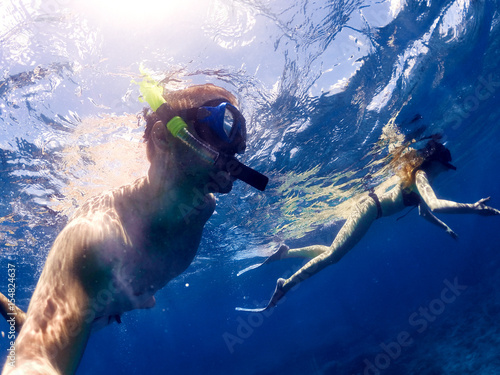 Couple snorkeling in deep blue sea. Summer fun. Taking under water selfie.