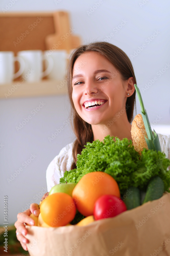 Young woman holding grocery shopping bag with vegetables Young woman holding grocery shopping bag with vegetables