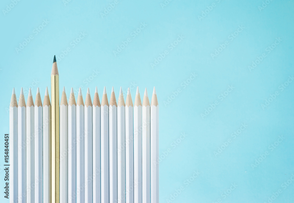 Business concept - lot of white pencils and one color pencil stand on blue paper background like fence. It's symbol of leadership, teamwork, united and communication. Business concept - lot of white pencils and one color pencil stand on blue paper background like fence. It's symbol of leadership, teamwork, united and communication.