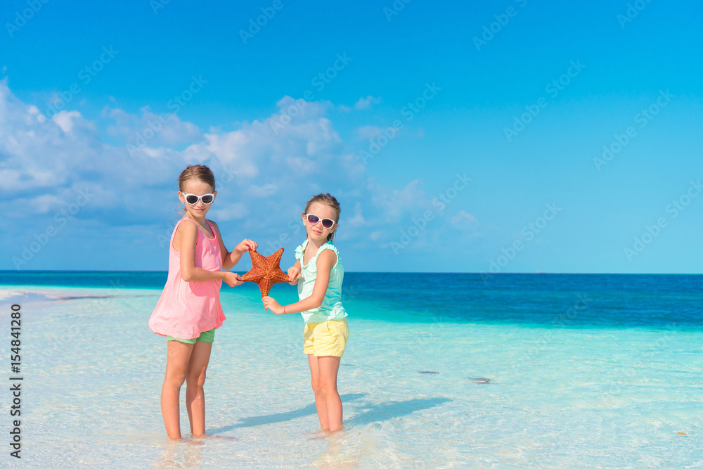 Adorable little girls holding giant red starfish