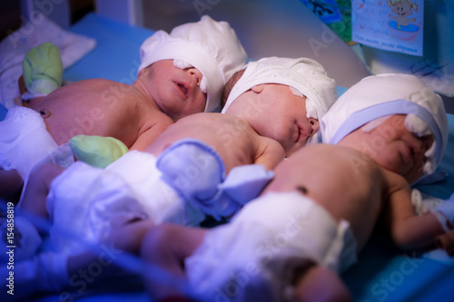 Newborn triplets baby are under the device with ultraviolet radiation in the maternity hospital photo
