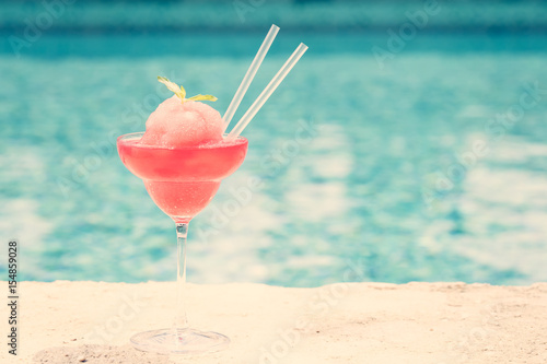 Frozen strawberry margarita cocktail at the edge of a resort pool. Concept of luxury vacation