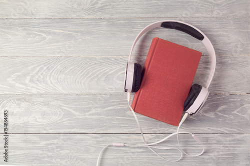 Audio book concept with old book and headphones. View from above. Flat lay photo