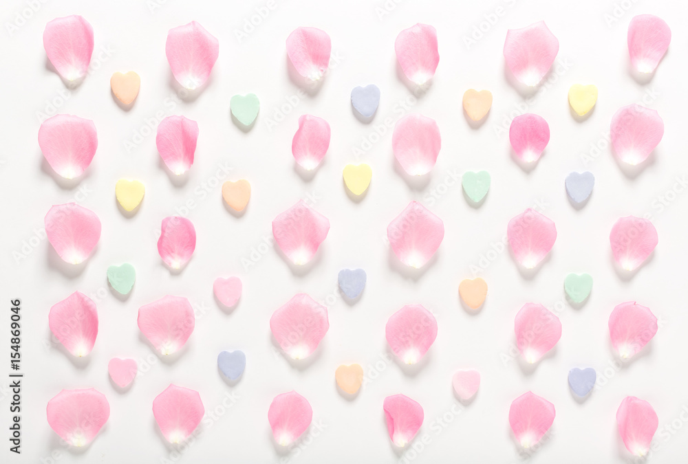 Candy hearts and rose petals on a white background