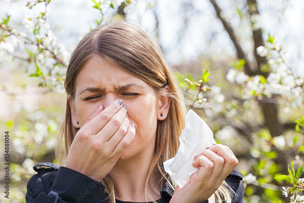 Allergic woman sneezing outdoor on springtime Allergic woman sneezing outdoor on springtime