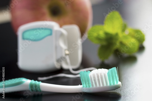 Toothbrush  dental floss  apple and peppermint on table.