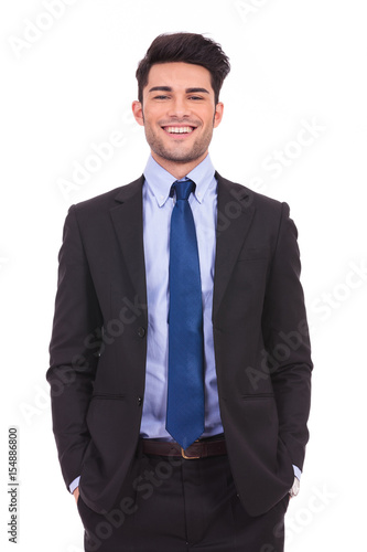 laughing young businessman standing with hands in pockets