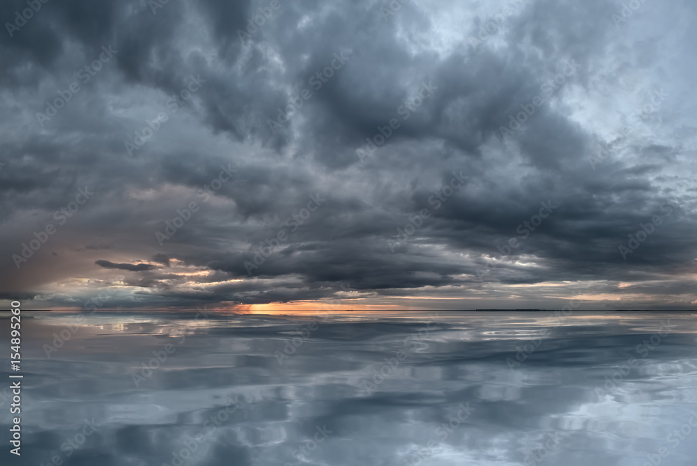 Fototapeta premium Sunset by the sea, with a gloomy sky