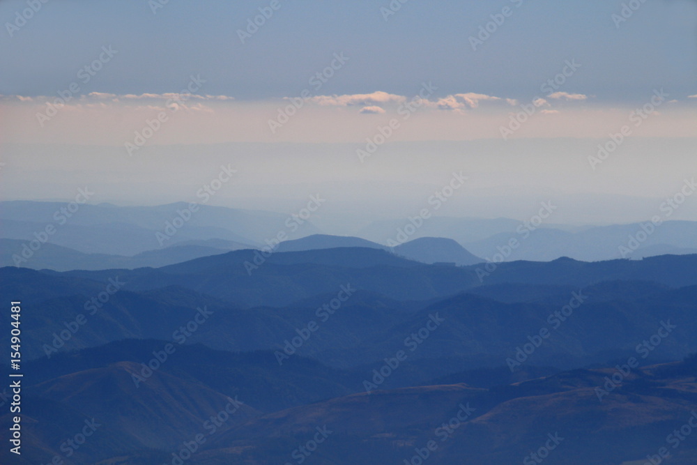 Hazy blue ridges of Slovak Ore Mountains and Slovak Paradise National Park under white clouds from Lomnicky peak, High Tatras, Slovakia, Europe