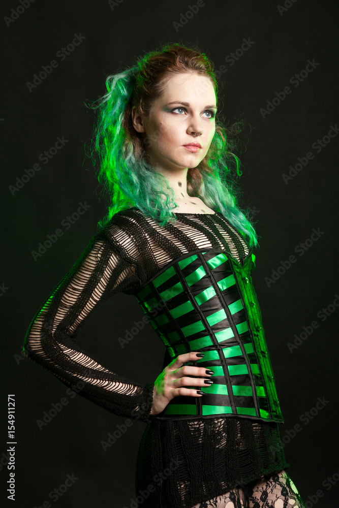Sexy Woman in cosplay corset posing in studio with a green light from behind. Studio photo. Fashion and cosplay Sexy Woman in cosplay corset posing in studio with a green light from behind. Studio photo. Fashion and cosplay