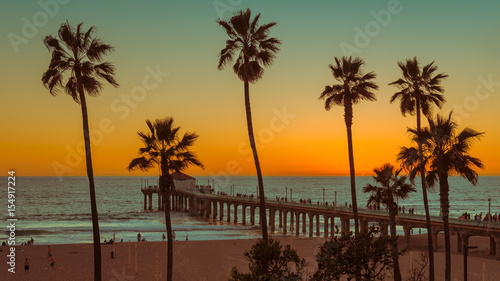Palm trees and Pier on Manhattan Beach at sunset in California, Los Angeles, USA. 
