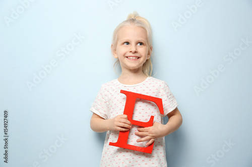 Cute little girl with letter E on light background