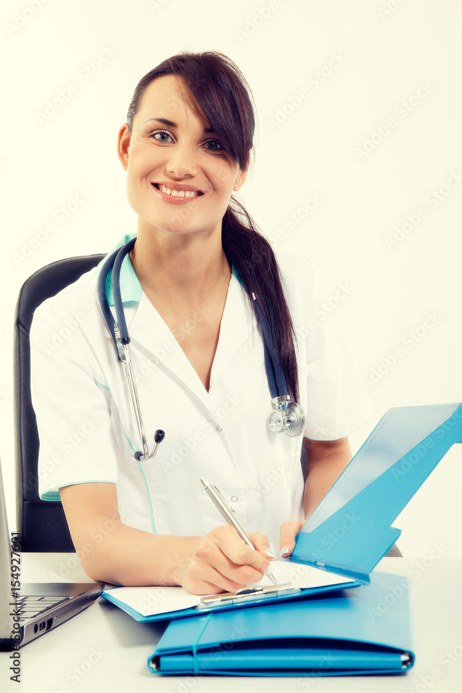 Female doctor sitting at office desk and smiling at camera Female doctor sitting at office desk and smiling at camera