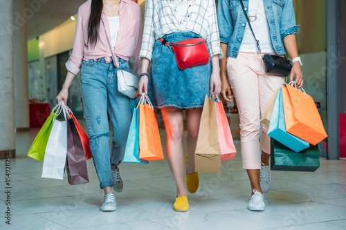 Cropped shot of young women with shopping bags walking in shopping mall, young girls shopping concept