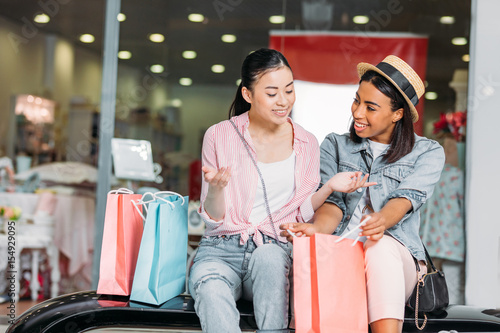 portrait of stylish women friends shopping together at shopping mall