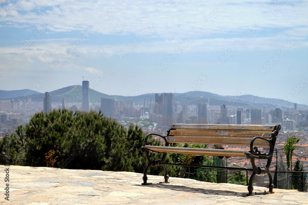 Public bench on the top of the hill with the city background Public bench on the top of the hill with the city background