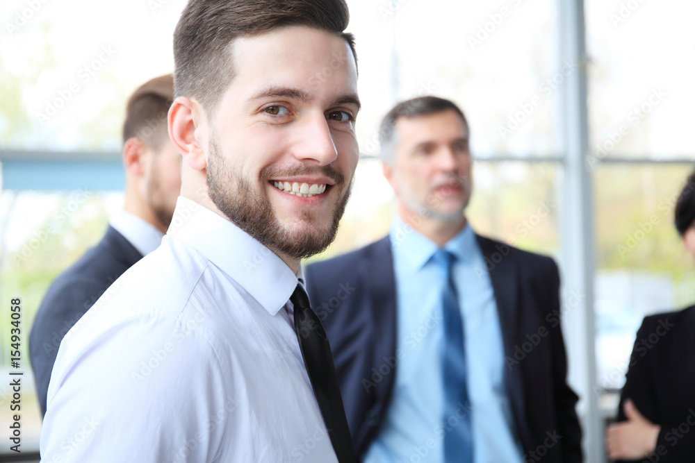 Happy smart business man with team mates discussing in the background. Happy smart business man with team mates discussing in the background.