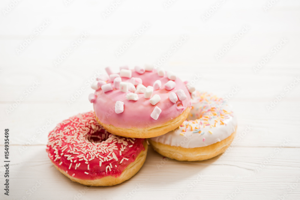Close Up view of three tasty donuts with frosting on the top lying on wooden table. appetizing chocolate donuts background