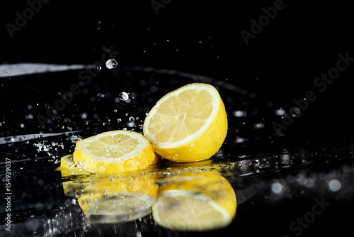 Close-up view of fresh sliced lemon with water drops isolated on black
