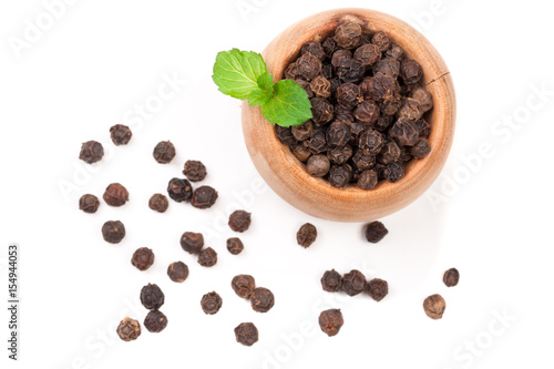 Black peppercorn in a wooden spoon isolated on white background. Top view