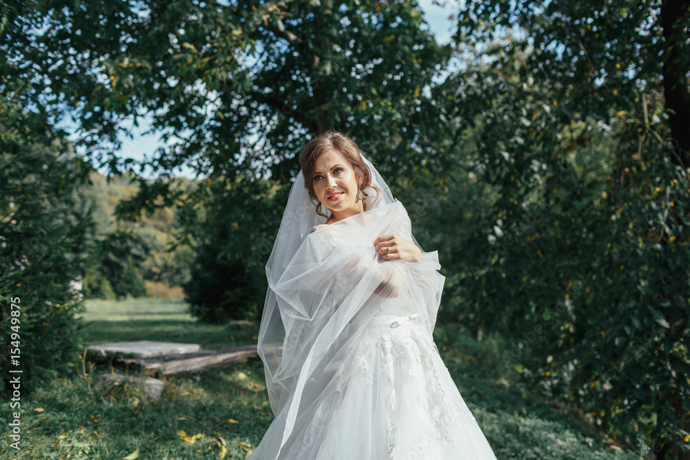 The charming bride stands in the park