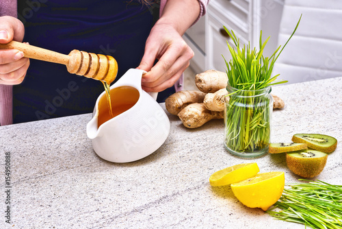Golden liquid Organic Honey on a drip pouring Green wheat, lemon and ginger f...