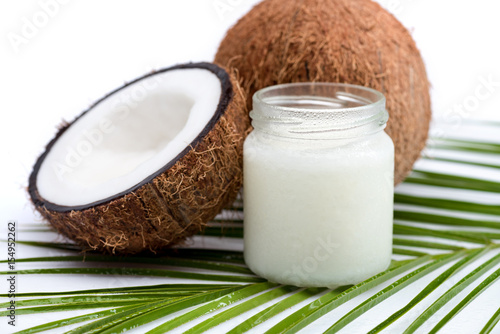 ripe coconuts and organic coconut oil in glass jar on coconut leaf  isolated on white