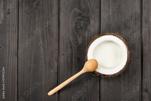 top view of ripe coconut half with milk and wooden spoon, coconut milk