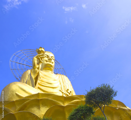 big golden buddha with blue sky and clouds.