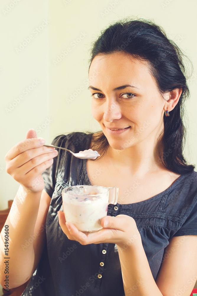 Beautiful young woman eating yogurt at home. Beautiful young woman eating yogurt at home.