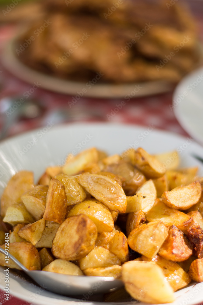 Fried young potatoes served on the lunch table with steaks in th Fried young potatoes served on the lunch table with steaks in th