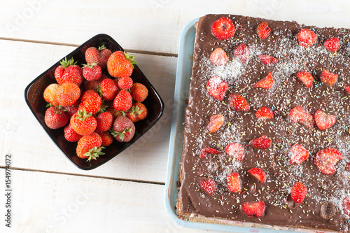 Flat lay chocolate cake with fresh strawberries in the bowl abov photo