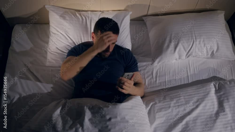 The man worrying about the information from the phone lying in the bed. 4K. The man worrying about the information from the phone lying in the bed. 4K.