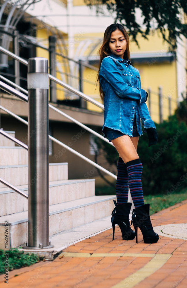 Fashionable pretty young woman wearing blue jeans, and long striped knee  socks Stock Photo | Adobe Stock