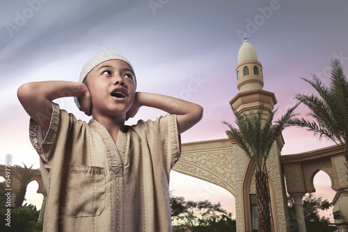 Asian muslim child with traditional dress praying photo