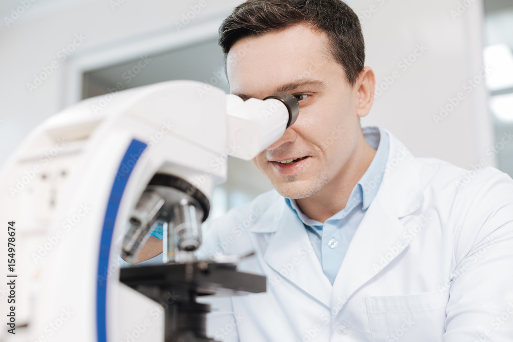 Positive delighted scientist looking into microscope Positive delighted scientist looking into microscope