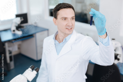 Competent lab assistant looking at test-tube