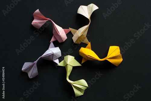 Oval frame figure of handmade paper craft origami gold koi carp fishes on black background.Top view