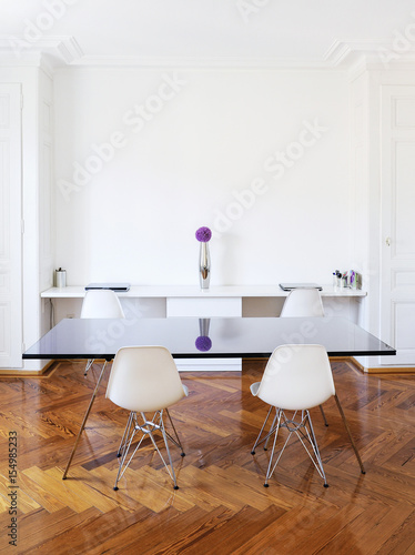 Salle à manger et bureau dans un bel immeuble hausmannien avec parquet en bois et mobilier design blanc et noir