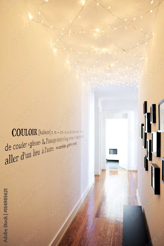 Long white corridor illuminated by a garland on the ceiling and decorated with a wall definition