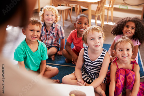 Obraz na płótnie Teacher At Montessori School Reading To Children At Story Time