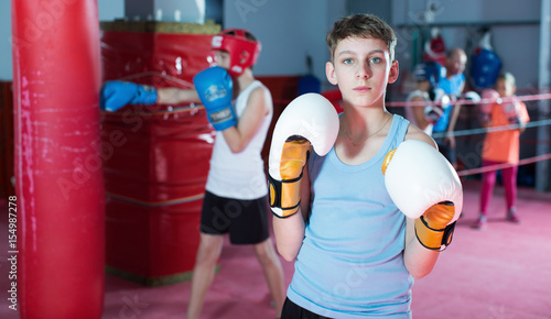Teenage boy boxer in gloves posing during boxing