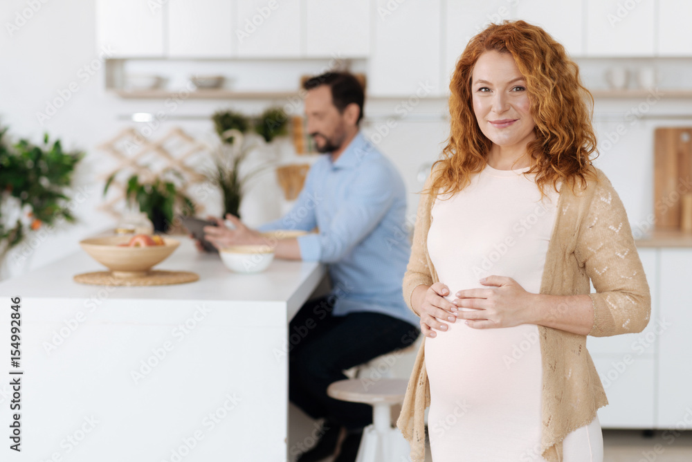 Mother-to-be posing with husband working on background