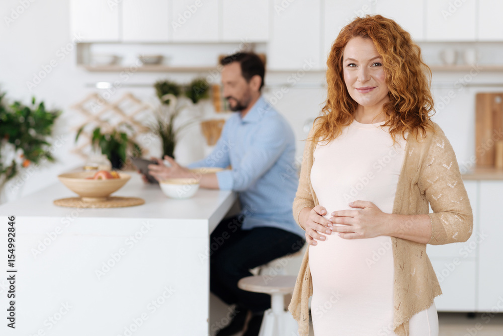 Mother-to-be posing with husband working on background Mother-to-be posing with husband working on background