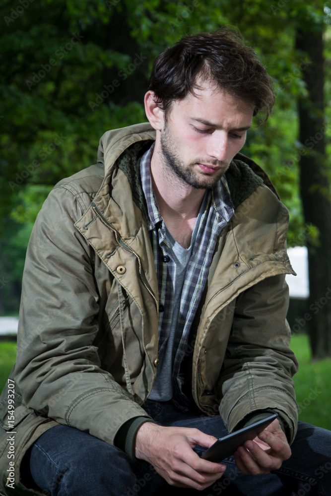 Young Man Reading With A Digital Tablet At The Park Young Man Reading With A Digital Tablet At The Park