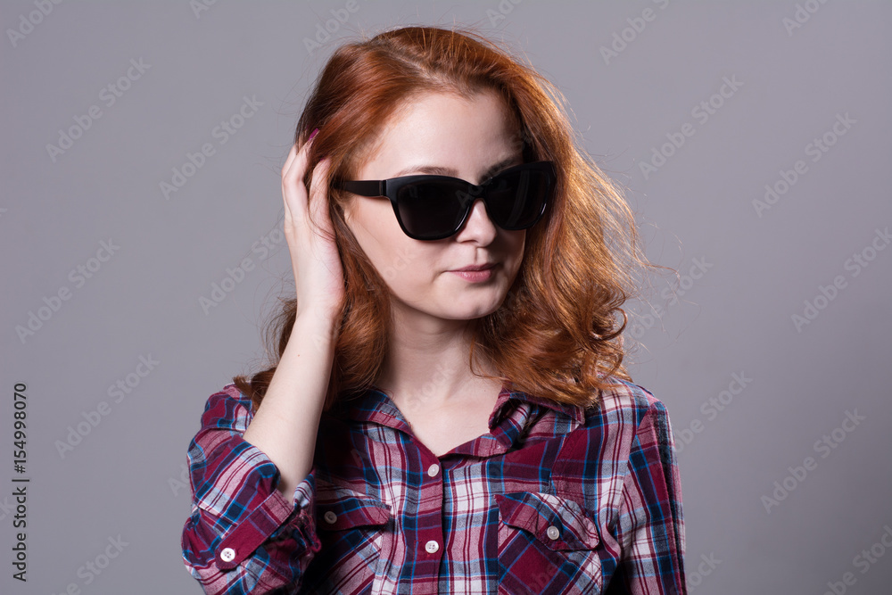 Close-up portrait of a red-haired beautiful woman wearing sunglasses Close-up portrait of a red-haired beautiful woman wearing sunglasses