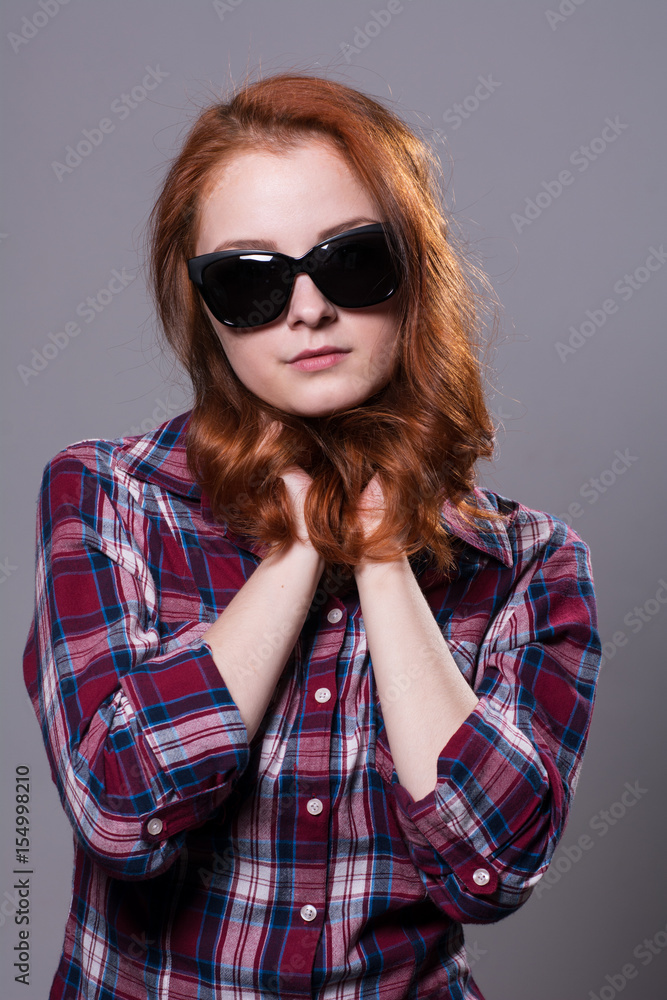 Portrait of a red-haired beautiful woman wearing sunglasses. Portrait of a red-haired beautiful woman wearing sunglasses.