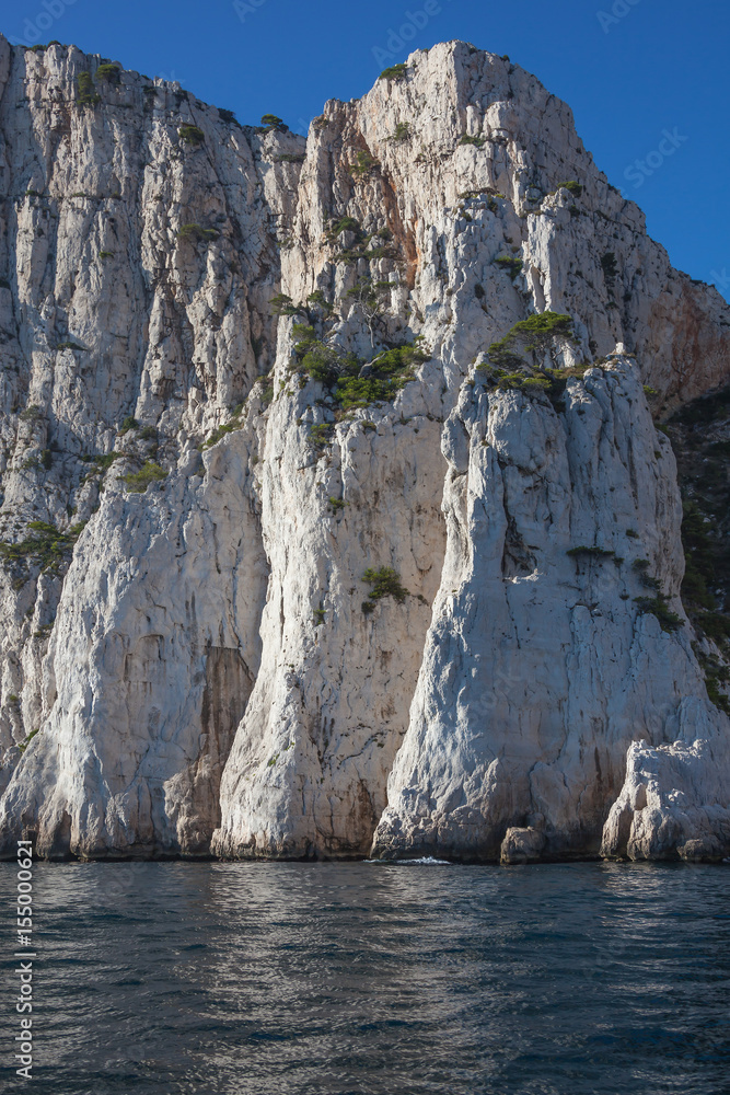 Famous white limestone cliffs rising out of the water on blue sky background in Calanques national park near Cassis, France