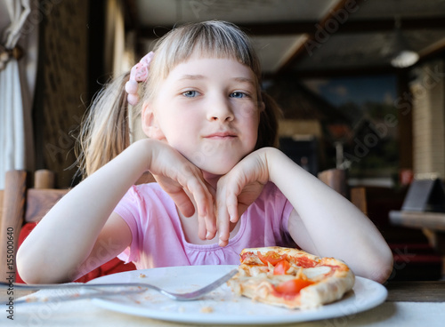 Full and glad child with a piece of a pizza