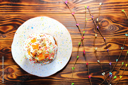 Cake with multi-colored powder for cake on white multicolored confetti plate and with tree sprigs on brown wooden boards photo